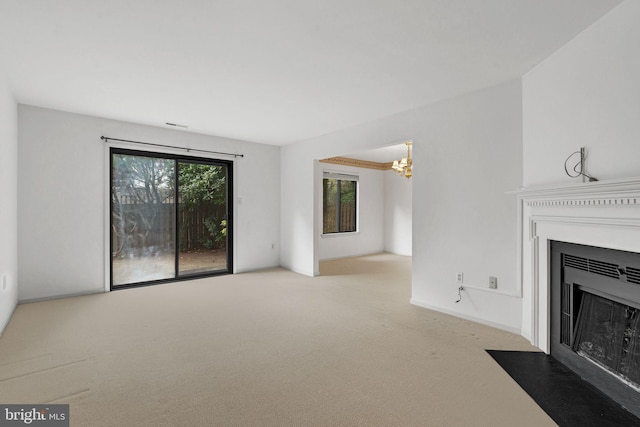 unfurnished living room featuring an inviting chandelier and light carpet