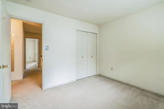 unfurnished bedroom with light carpet and a closet