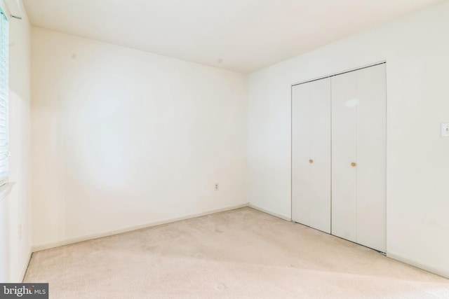 unfurnished bedroom featuring light carpet and a closet