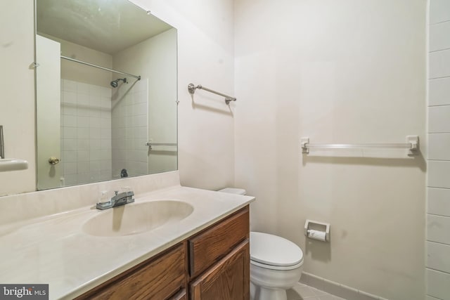 bathroom featuring vanity, tiled shower, and toilet