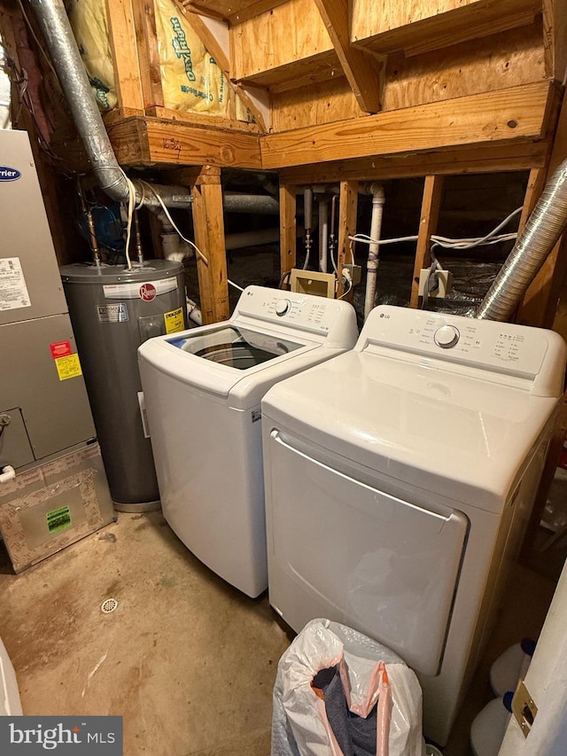 clothes washing area featuring washing machine and dryer, electric water heater, and heating unit