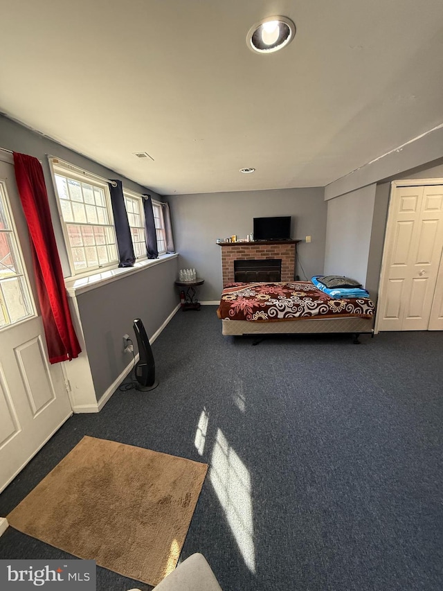 bedroom with a brick fireplace and dark carpet