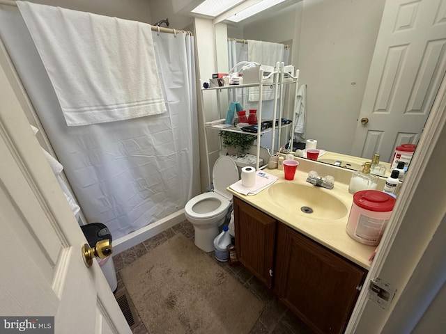 bathroom with vanity, curtained shower, a skylight, and toilet