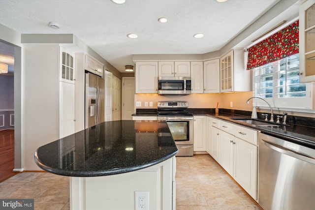 kitchen with appliances with stainless steel finishes, a center island, sink, and white cabinets