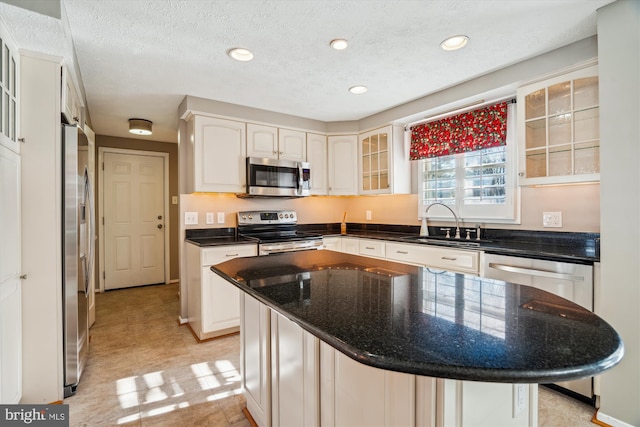 kitchen featuring sink, white cabinetry, a textured ceiling, a kitchen island, and stainless steel appliances