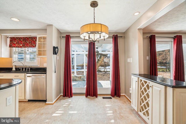 kitchen with a wealth of natural light, sink, stainless steel dishwasher, and decorative light fixtures