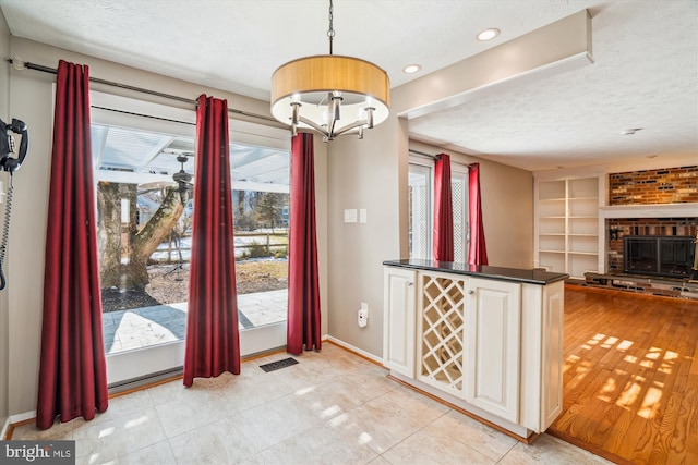 tiled entrance foyer featuring a brick fireplace and a textured ceiling