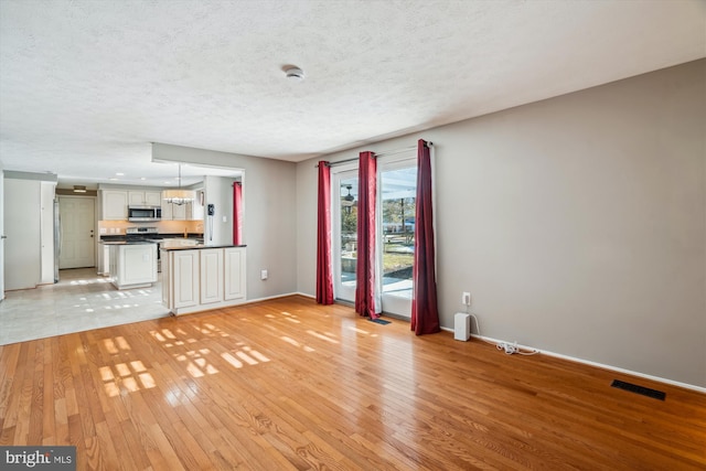 unfurnished living room with light hardwood / wood-style floors and a textured ceiling