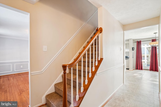 stairway with tile patterned floors and a textured ceiling