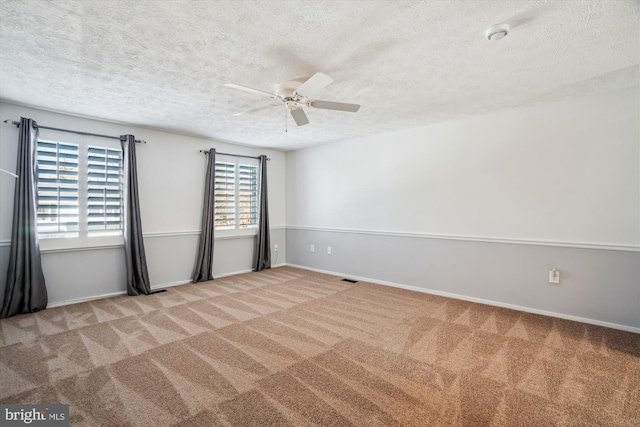 spare room featuring ceiling fan, light carpet, and a textured ceiling