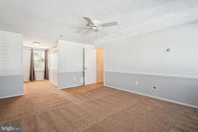 empty room with ceiling fan, light carpet, and a textured ceiling