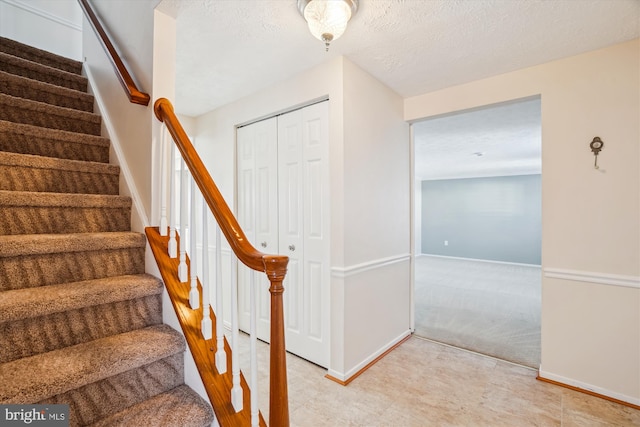 stairs featuring a textured ceiling