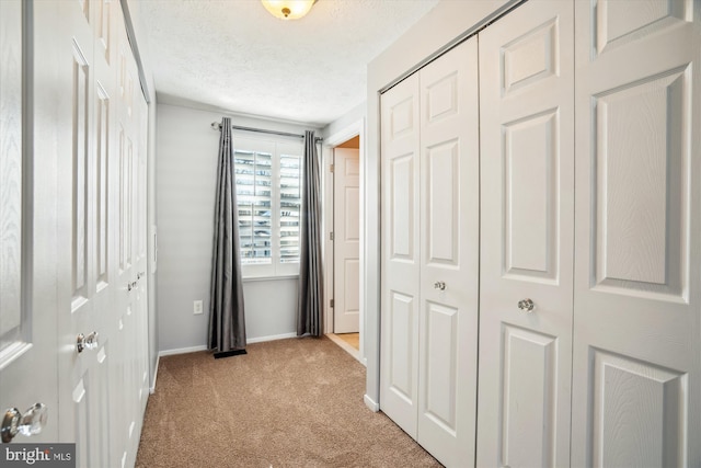 corridor with light carpet and a textured ceiling