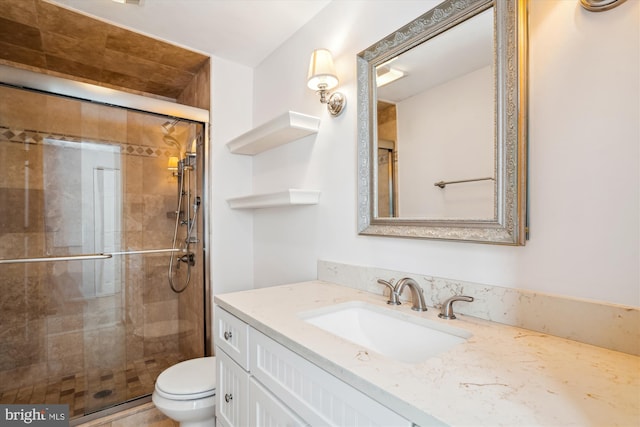 bathroom featuring vanity, toilet, and a shower with shower door