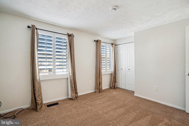 unfurnished bedroom with light colored carpet, a textured ceiling, and a closet