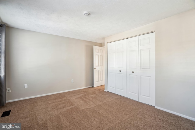 unfurnished bedroom featuring carpet floors, a textured ceiling, and a closet