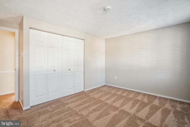 unfurnished bedroom with carpet floors, a closet, and a textured ceiling