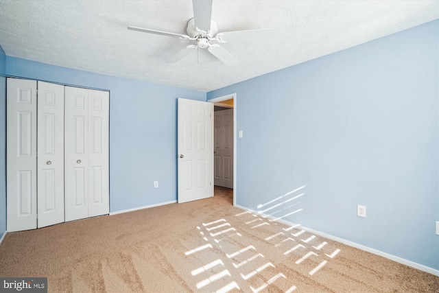 unfurnished bedroom featuring ceiling fan, light colored carpet, a textured ceiling, and a closet