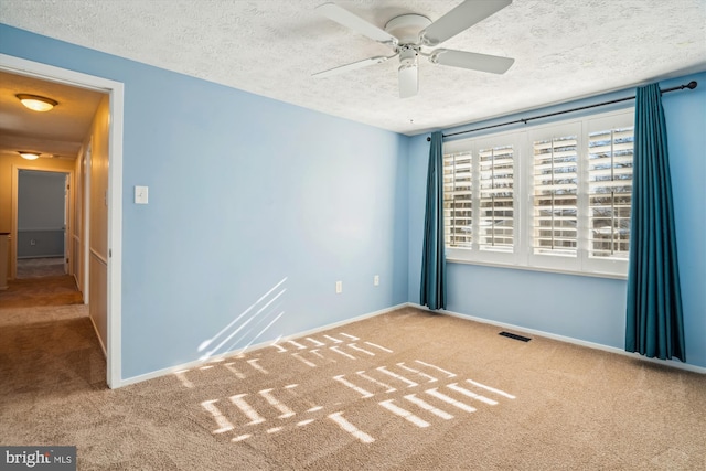 carpeted spare room featuring ceiling fan and a textured ceiling