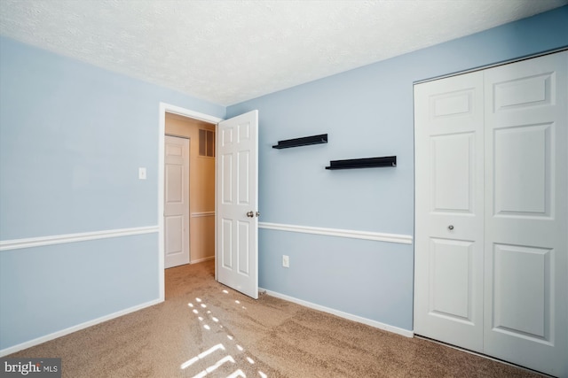 unfurnished bedroom with light carpet, a textured ceiling, and a closet