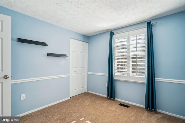 unfurnished bedroom with a closet, light carpet, and a textured ceiling