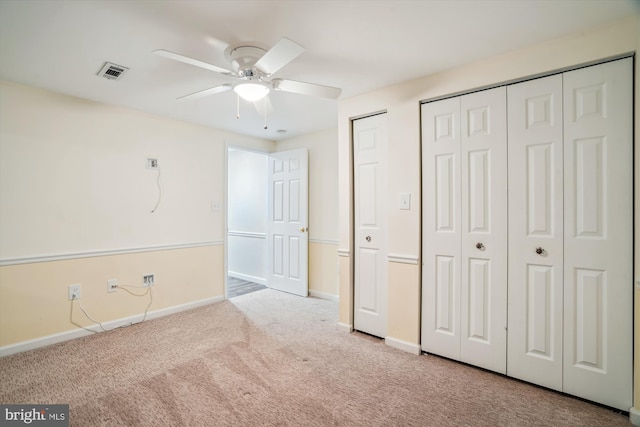 unfurnished bedroom with two closets, light carpet, and ceiling fan