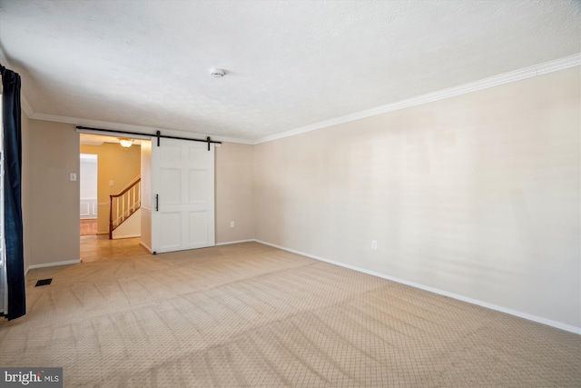 empty room with ornamental molding, a barn door, and light colored carpet