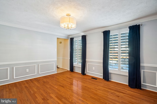 empty room with a textured ceiling, a wealth of natural light, and wood-type flooring