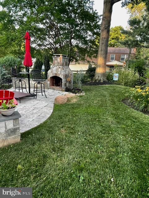 view of yard featuring a patio area and an outdoor stone fireplace