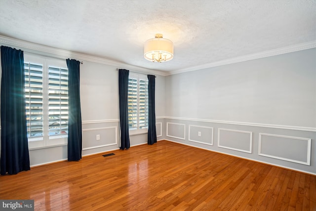 empty room featuring hardwood / wood-style flooring, ornamental molding, and a textured ceiling