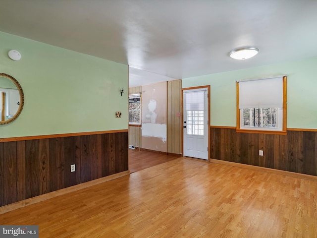 unfurnished room with light hardwood / wood-style flooring and wooden walls