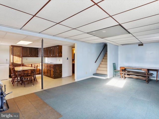 interior space featuring light carpet, a paneled ceiling, and refrigerator