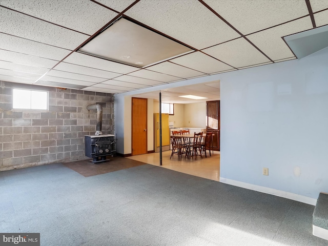 basement with a drop ceiling and a wood stove