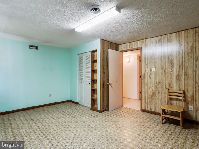 spare room with a textured ceiling and wood walls