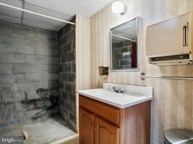 bathroom featuring walk in shower, a paneled ceiling, and vanity