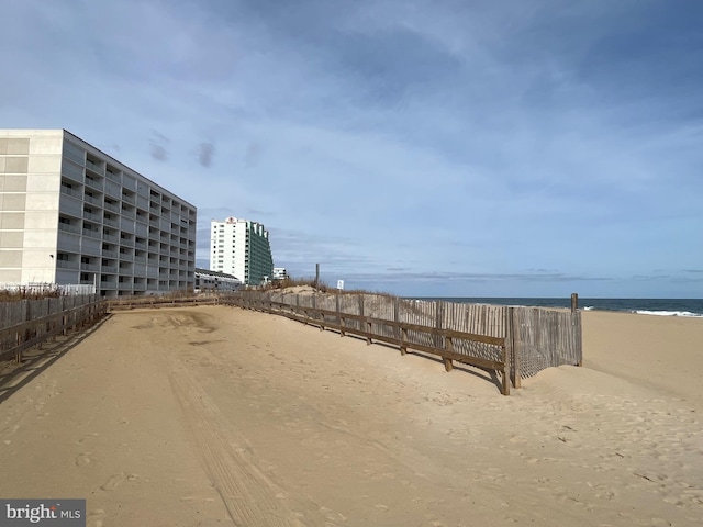 exterior space featuring a water view, fence, and a view of the beach