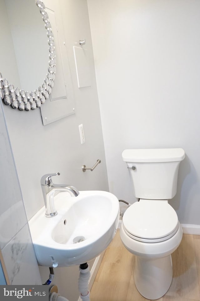 half bathroom with a sink, wood finished floors, toilet, and baseboards