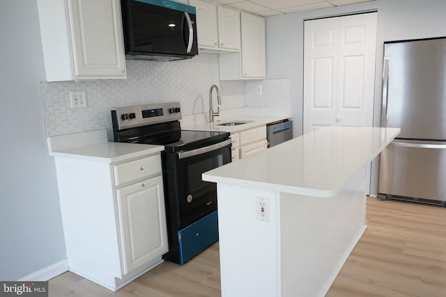 kitchen with light wood-style floors, appliances with stainless steel finishes, a sink, and a center island