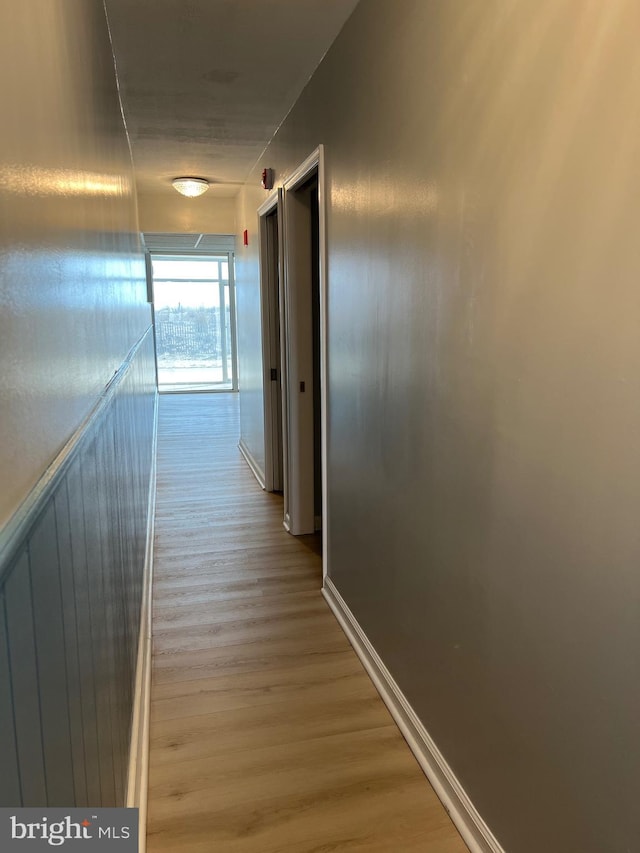 corridor with light wood-type flooring and baseboards