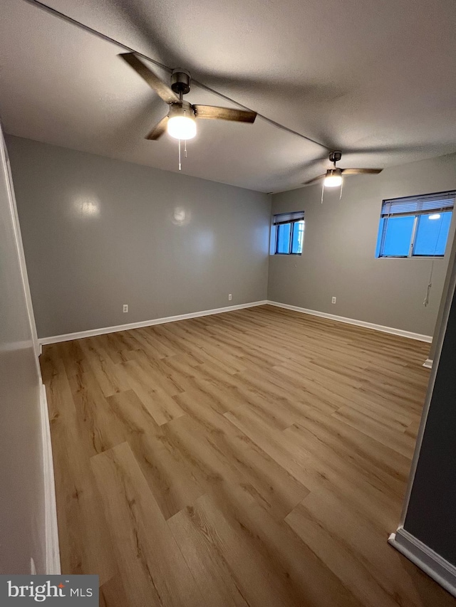 spare room with ceiling fan, a textured ceiling, baseboards, and wood finished floors