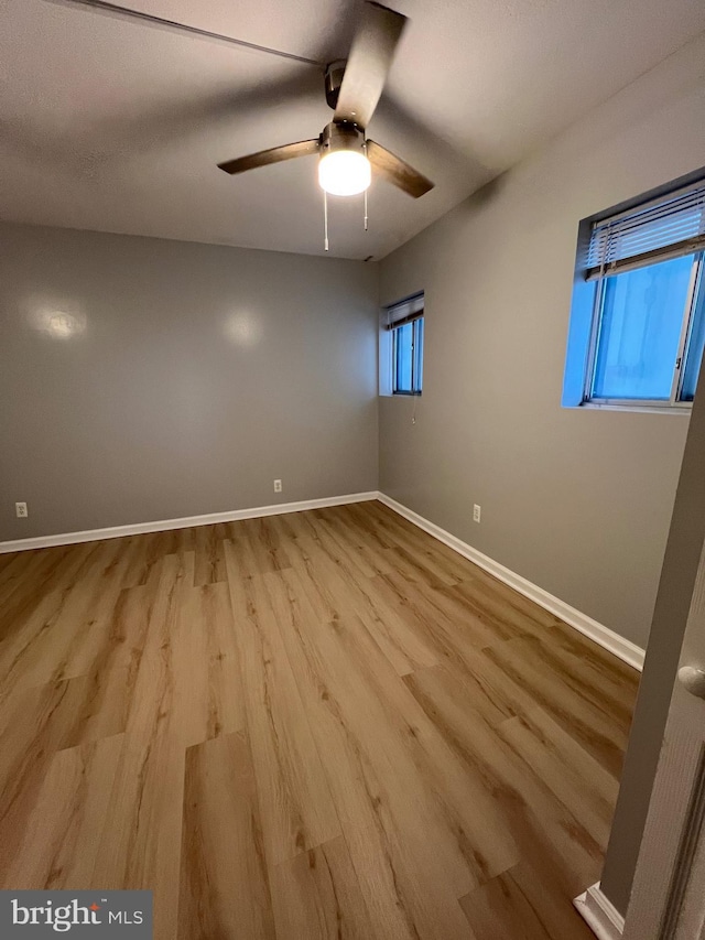 unfurnished room with a ceiling fan, baseboards, and wood finished floors