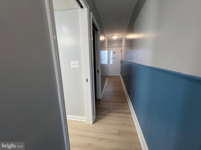 hallway with light wood-type flooring and wainscoting