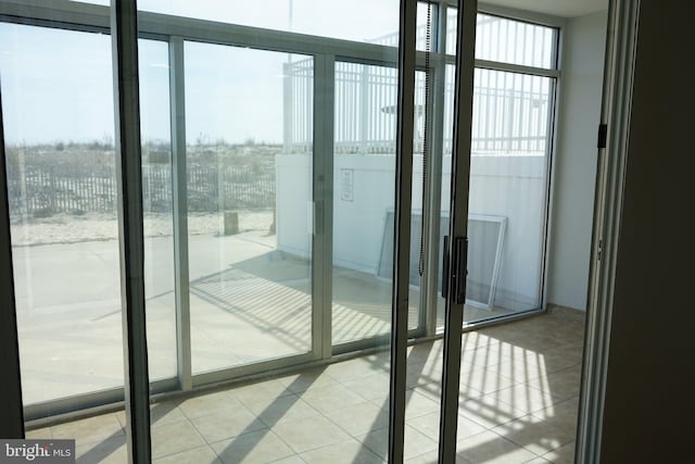 doorway to outside with a wall of windows and tile patterned floors