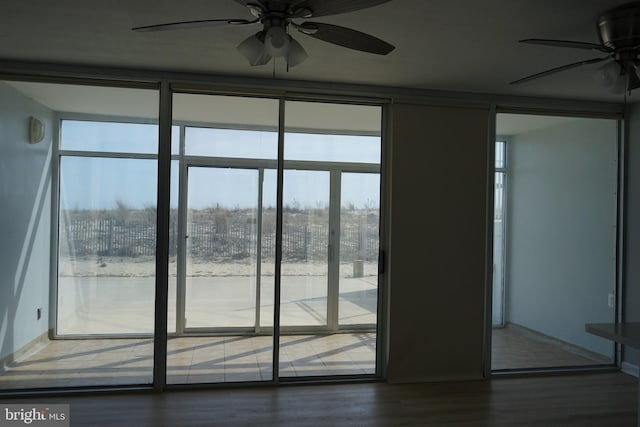 entryway featuring ceiling fan, baseboards, wood finished floors, and floor to ceiling windows