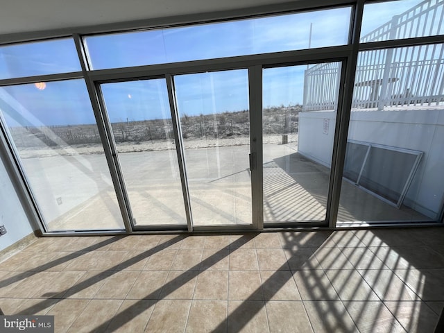 doorway featuring a healthy amount of sunlight, baseboards, and tile patterned floors