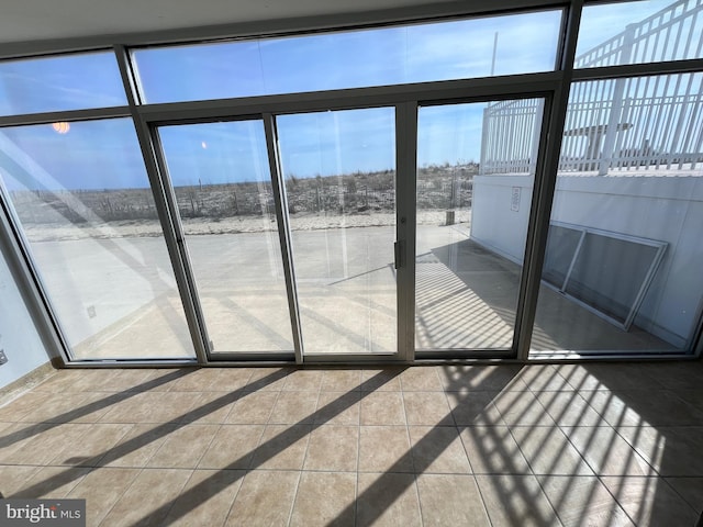 doorway to outside featuring tile patterned flooring, a healthy amount of sunlight, and baseboards