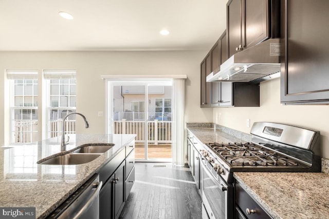 kitchen with sink, stainless steel appliances, light stone counters, dark brown cabinetry, and dark hardwood / wood-style flooring