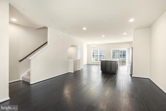 unfurnished living room featuring a chandelier and dark hardwood / wood-style flooring