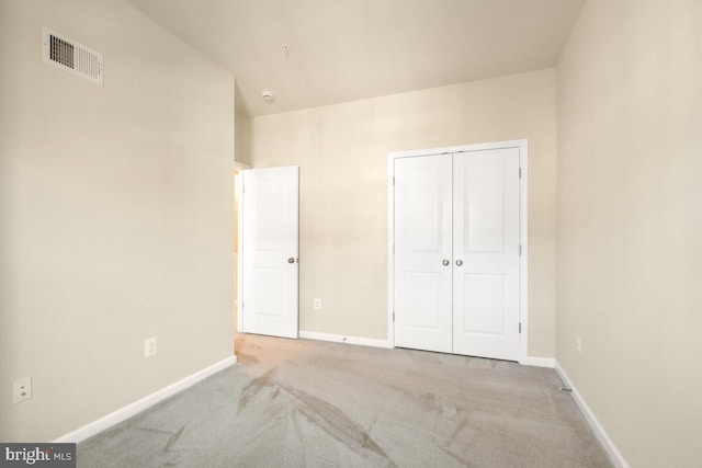 unfurnished bedroom with light colored carpet and a closet