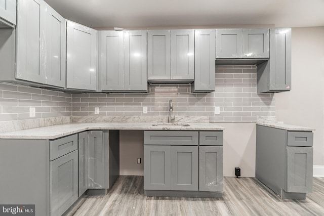 kitchen featuring light wood-style floors, gray cabinets, and a sink